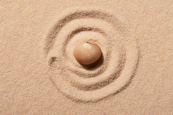 Espiral desenhado na areia da praia com pedra rosa redonda do mar — Fotografia de Stock