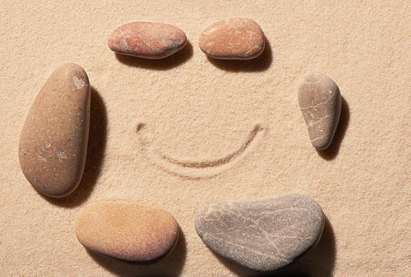 Pequenas e grandes pedras marinhas com sorriso desenhado na areia — Fotografia de Stock