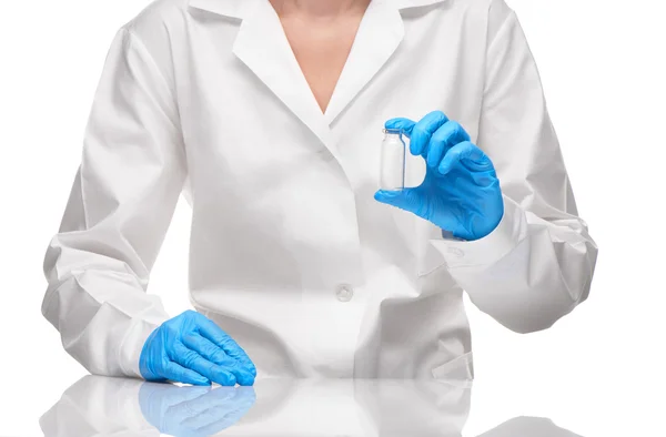 Doctor in gown and gloves holding empty ampoule against white — Stock Photo, Image