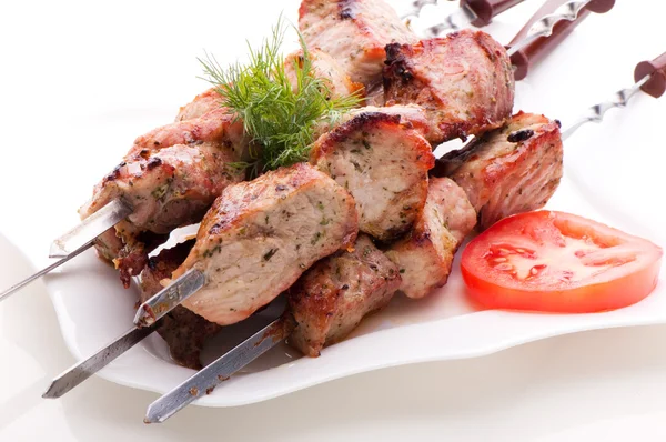 Кусочки свежего жареного мяса на шампуре, лежащие на белой тарелке — стоковое фото