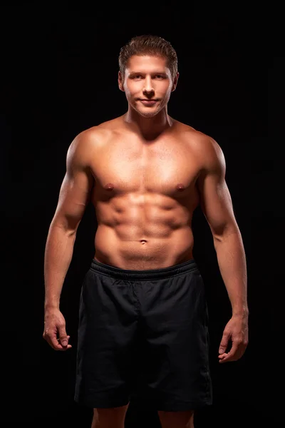 Muscular smiling powerful man on black background — 图库照片
