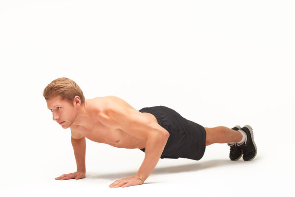 Sportsman making push-ups on palms in studio with bent arms