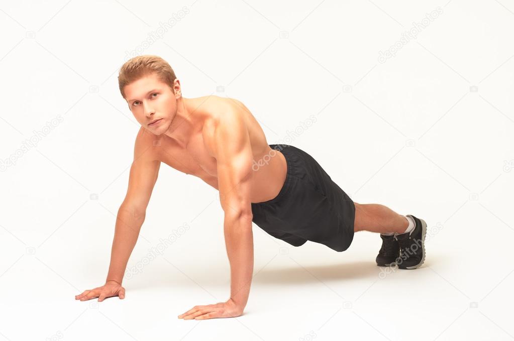 Sportsman making push-ups on palms in studio with straight arms