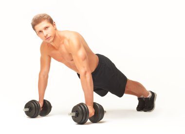Muscular sportsman doing push-ups with dumbbells on white background