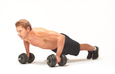 Muscular sportsman doing push-ups with dumbbells on white background