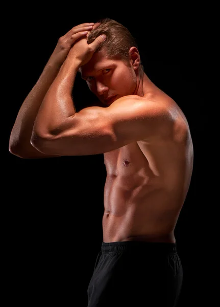Sexy shirtless young muscular sportsman demonstrating biceps, pectoral, abs muscles