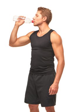 Thirsty handsome muscular young sportsman drinking water after hard workout