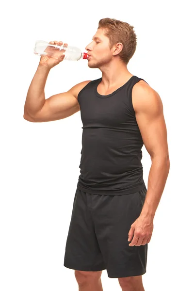 Thirsty handsome muscular young sportsman drinking water after hard workout