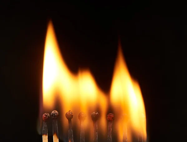 Sada osmi hořící dřevěné zápalky, izolované na černém pozadí — Stock fotografie