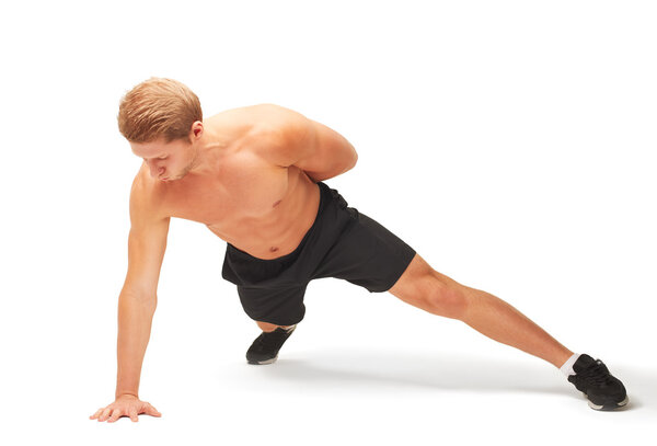 Young muscular handsome shirtless sportsman doing push-ups on one arm