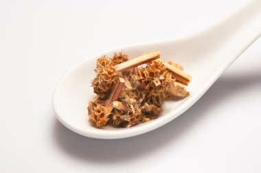 Yığın beyaz arka plan üzerinde beyaz Seramik kaşık kuru tıbbi bitkisel çay