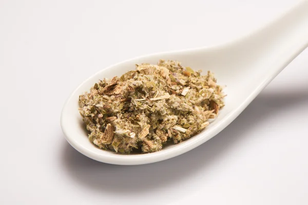 Hromadu suchého lékařský bylinné čaje v bílé keramické lžíce — Stock fotografie