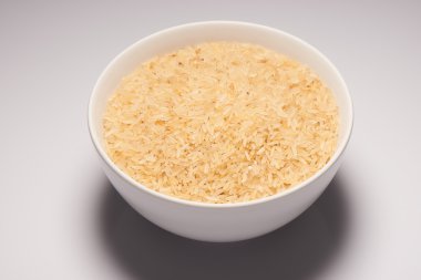 Kahverengi pirinç tohumu beyaz arka plan üzerinde beyaz seramik kase