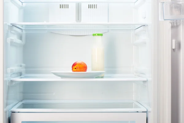 Peach on white plate with bottle of yogurt in refrigerator — Stock Photo, Image