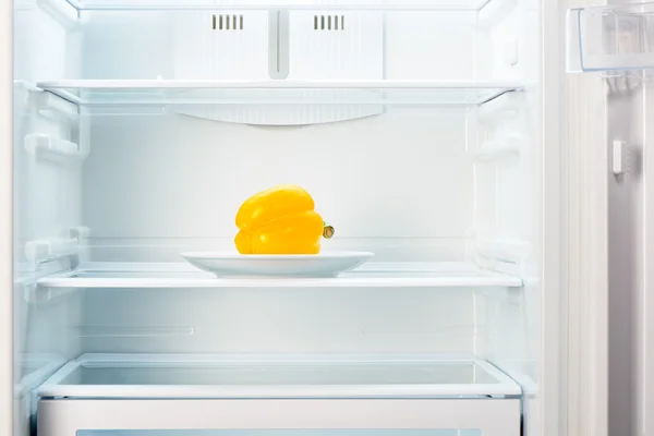 Pimenta amarela na placa branca no refrigerador vazio aberto — Fotografia de Stock