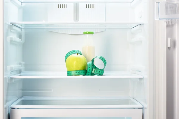 Apfel mit Maßband und Flasche im Kühlregal — Stockfoto