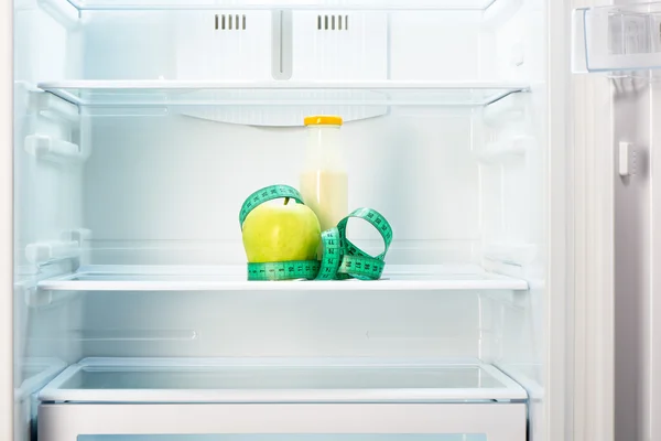 Apfel mit Maßband und Flasche im Kühlregal — Stockfoto