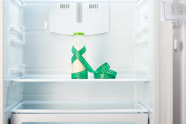 Garrafa de iogurte com fita métrica na prateleira do refrigerador — Fotografia de Stock