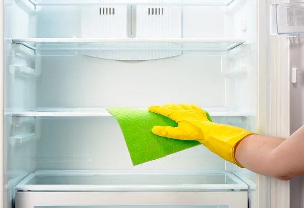 Frauenhand in gelbem Handschuhreiniger-Kühlschrank mit grünem Lappen — Stockfoto