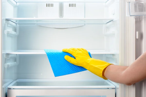 Mano de mujer en guante amarillo limpieza refrigerador con trapo azul —  Fotos de Stock