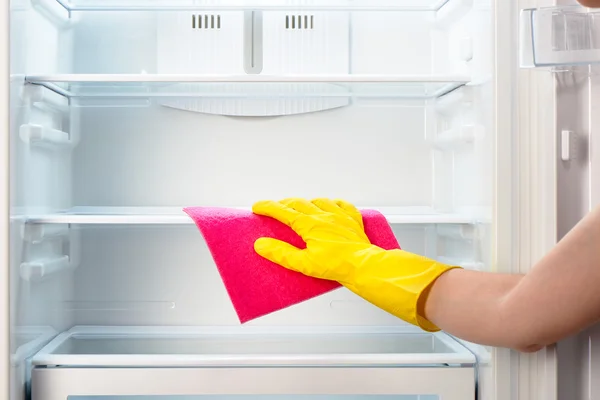 Ręka kobiety w żółtej rękawiczce Czyszczenie lodówki z różową szmatą — Zdjęcie stockowe