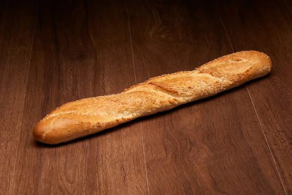 Pan baguette francés sobre mesa de madera oscura —  Fotos de Stock