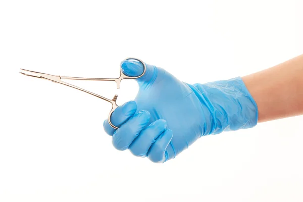 Close up da mão do médico feminino em azul luva cirúrgica esterilizada com fórceps contra branco — Fotografia de Stock