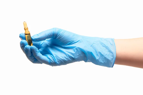 Крупним планом жіноча рука лікаря в синій стерилізованій хірургічній рукавичці, що тримає коричневу скляну ампулу з препаратом — стокове фото