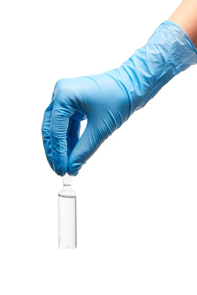 Primer plano de la mano de la doctora en guante quirúrgico esterilizado azul que sostiene una ampolla de vidrio blanco con una droga contra el blanco — Foto de Stock
