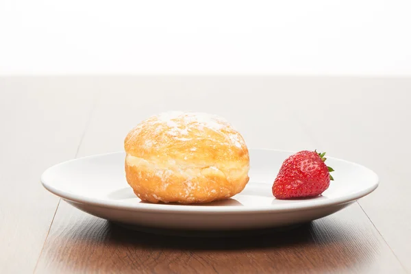 Ringdiagram met slagroom suiker en aardbei op witte keramische plaat op heldere licht bruin houten tafel — Stockfoto