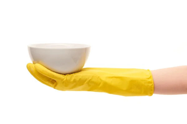 Main féminine en gant de caoutchouc jaune tenant un bol blanc propre — Photo