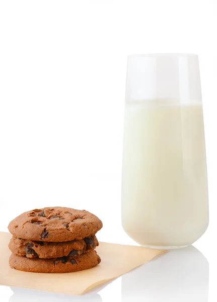 Three homemade chocolate chip cookies on baking paper and glass of milk — Stock Photo, Image