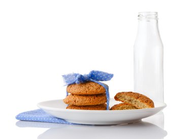 Küçük beyaz lekeli ve çerezleri peçete ve boş süt şişesi üzerinde beyaz tabakta yarısı mavi kurdele ile yulaf ezmeli kurabiye bağlı