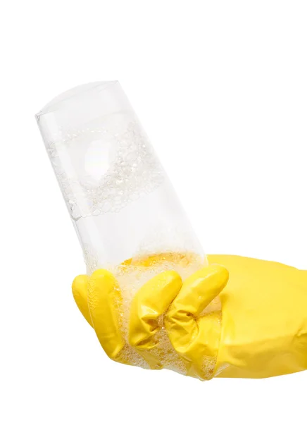 Hand in yellow rubber glove holding clean transparent drinking glass in foam — Stock Photo, Image