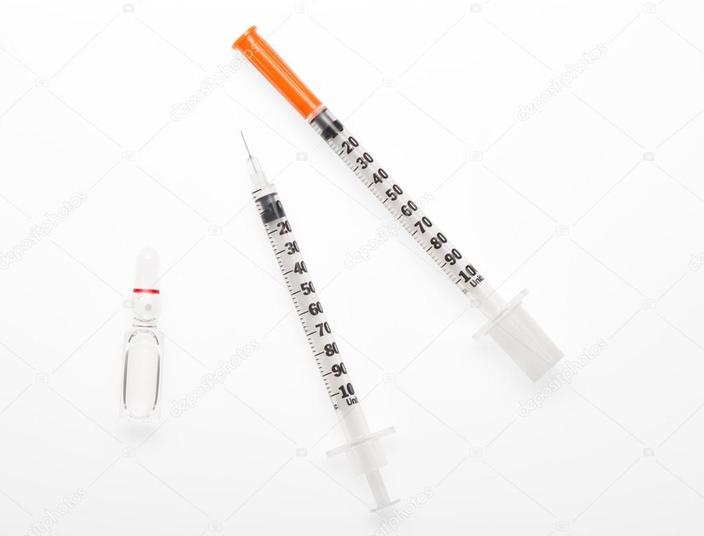 Plastic syringe with needle closed by protective cap, plastic syringe with open needle and transparent white glass ampoule with a drug
