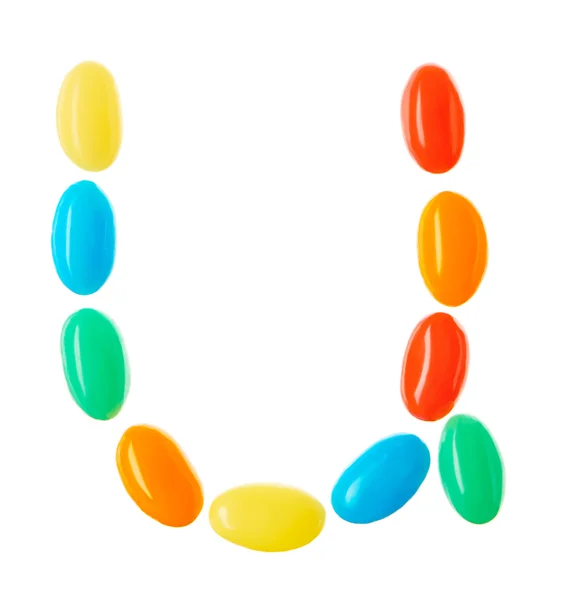 Carta en U hecha de caramelos multicolores aislados en blanco — Foto de Stock