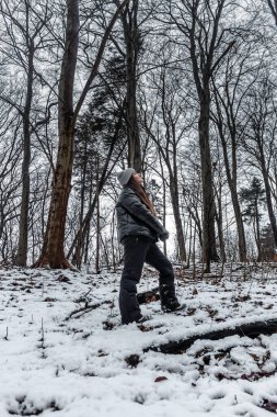 Genç bir kadın, Danimarka 'da bir ormanda sıcak giysiler giyerek karın tadını çıkarıyor.