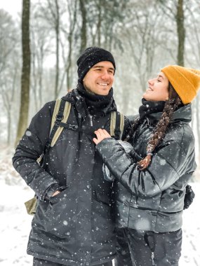 Genç çift gülüyor ve ormanın ortasında karın tadını çıkarıyor.