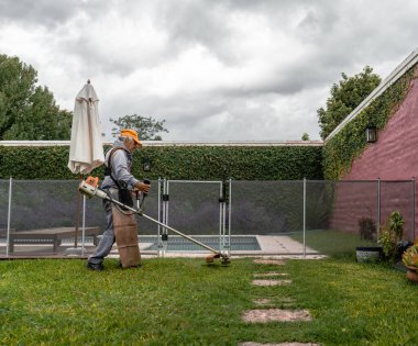 Bahçıvan bir evin arka bahçesinde çalışıyor.