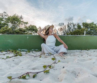 Kumda oturan şapkalı genç bir kadın.