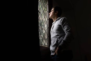 Pencereden dışarı bakan genç düşünceli adam - evde kal - inandırıcı kavram