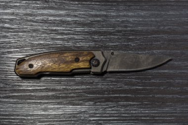 Açık bıçak siyah ahşap arka plan üzerine katlanmış.