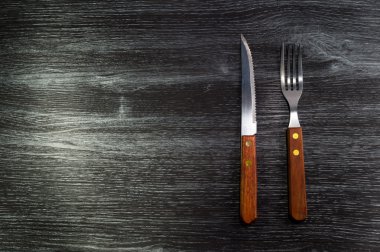 Çatal ve bıçak siyah ahşap doku arka plan üzerinde