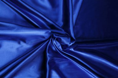 Renkli mavi tekstil kumaşı kıvrım kıvrım kıvrım ve dalgalar halinde ışık saçar.