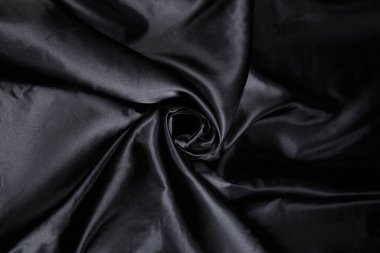 Renkli siyah tekstil kumaşı kıvrımlar ve dalgalar halinde kıvrılmış, parlak ışık ve desen parıldıyor.