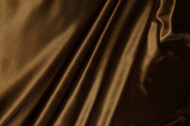 Renkli kahverengi tekstil kumaşı kıvrımlar ve dalgalar halinde kıvrılmış, parlak ışık ve desen parıldıyor.