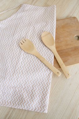 Sabahları hafif bir İskandinav mutfağında, önlüğün üzerinde bir tahta kaşık ve çatal yatar.