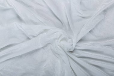 Renkli beyaz tekstil kumaşı kıvrımlar ve dalgalar halinde kıvrılmış, parlak ışık ve desen parıldıyor.