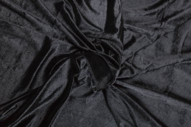 Renkli siyah tekstil kumaşı kıvrımlar ve dalgalar halinde kıvrılmış, parlak ışık ve desen parıldıyor.