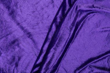 Renkli mor renkli tekstil kumaş kıvrımlar ve dalgalar halinde kıvrılmış, parlak ışık ve desen parıldıyor.